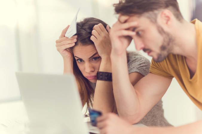 Couple in emotional distress staring at laptop screen